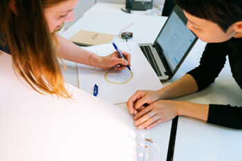 Closeup of two people drawing on large pieces of paper