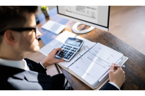 Accountant calculating invoices at desk with computer