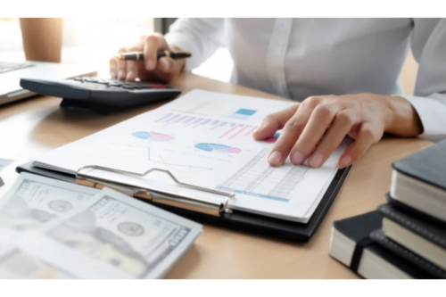 An accountant reviewing financial charts with calculator and documents.